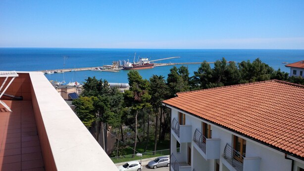 A coastal view with a marina, buildings with red-tiled roofs, and parked cars. - Penthouse Anna, in the center of a small town with a splendid sea view (Ortona)
