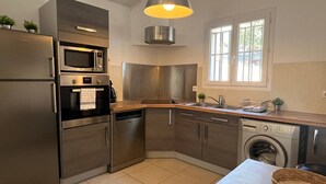Een compacte keuken met roestvrijstalen apparatuur, een inbouwoven, magnetron, vaatwasser en wasmachine.