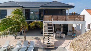 Una casa moderna de dos pisos con balcón, escalera y mobiliario exterior.