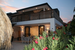 Stunning two-story residence with a flat roof and balcony, surrounded by a beautifully maintained garden.