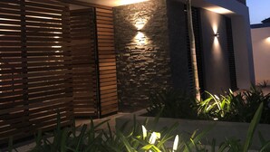 Un edificio moderno con fachada de piedra, listones de madera y una entrada bien iluminada.