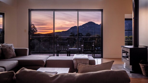 Un ampio soggiorno con un'ampia porta scorrevole in vetro che conduce a un balcone, un caminetto moderno e una zona salotto confortevole.