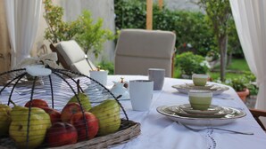 Ein Tisch ist mit Tellern, Tassen und einem Obstkorb gedeckt.