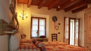 Ein gemütliches Schlafzimmer mit einem großen Bett, einem Holz-Kopfteil, einer Chandelüster und einem Fenster mit Vorhängen.