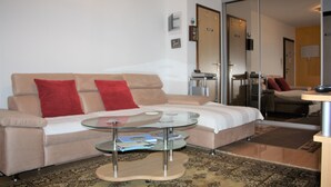 Un soggiorno moderno con un divano color beige, cuscini rossi, un tavolino in vetro e un tappeto decorato.