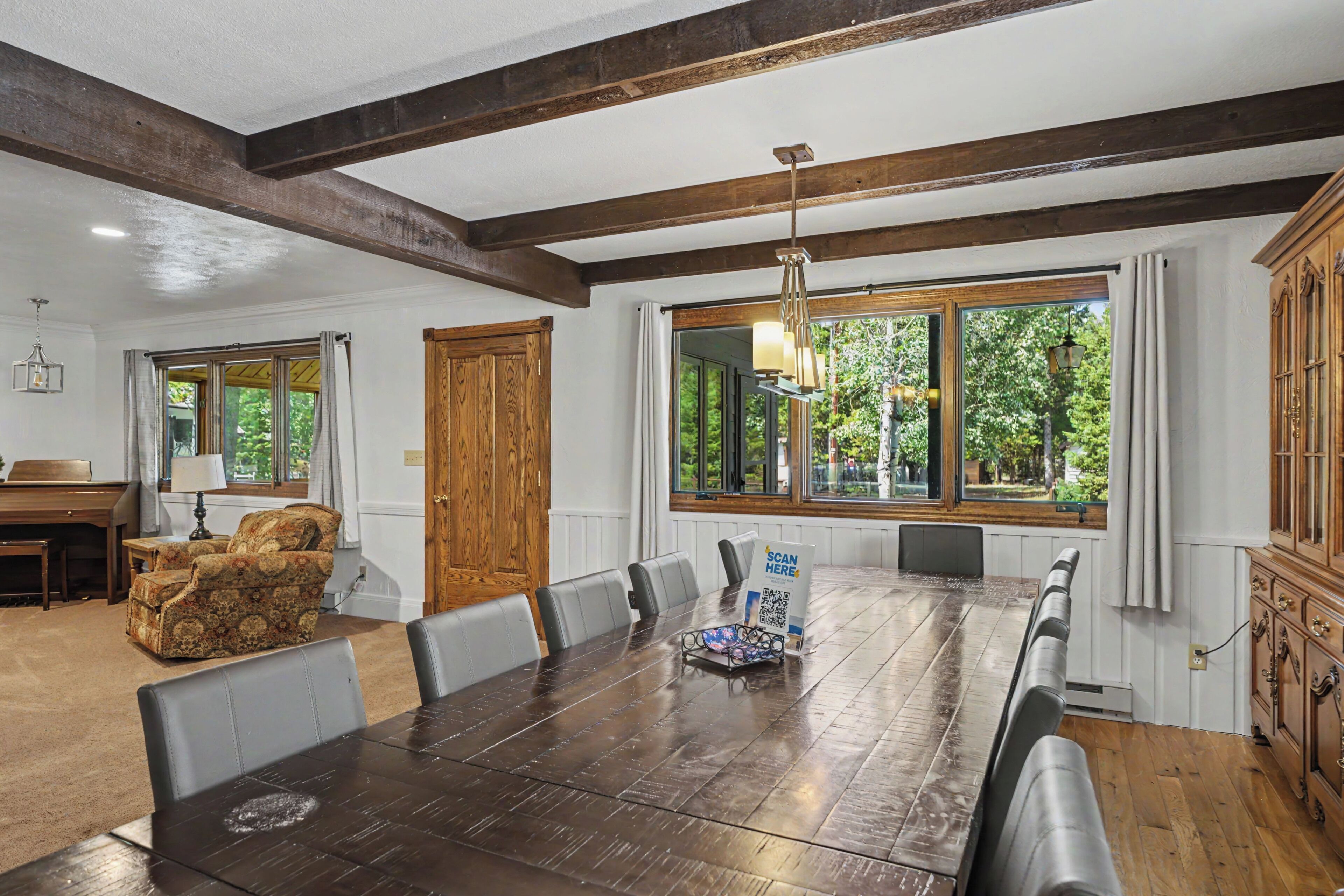 A dining area with a long wooden table, multiple chairs, and a chandelier.