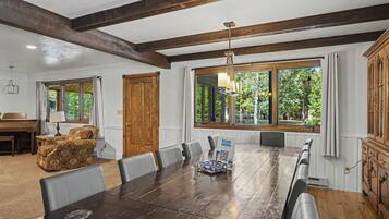 A dining area with a long wooden table, multiple chairs, and a chandelier.