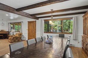 A dining area with a long wooden table, multiple chairs, and a chandelier. - Huge 3-bedroom home just 1 minute from Yellowstone. Legacy West (West Yellowstone)