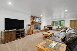 A living room with a television, fireplace, sofa, and windows. - Huge 3-bedroom home just 1 minute from Yellowstone. Legacy West (West Yellowstone)