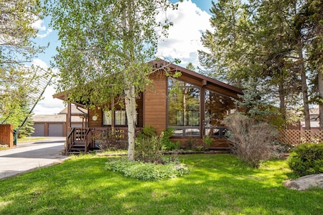 A single-story house with a front porch, large windows, and a well-maintained lawn.
