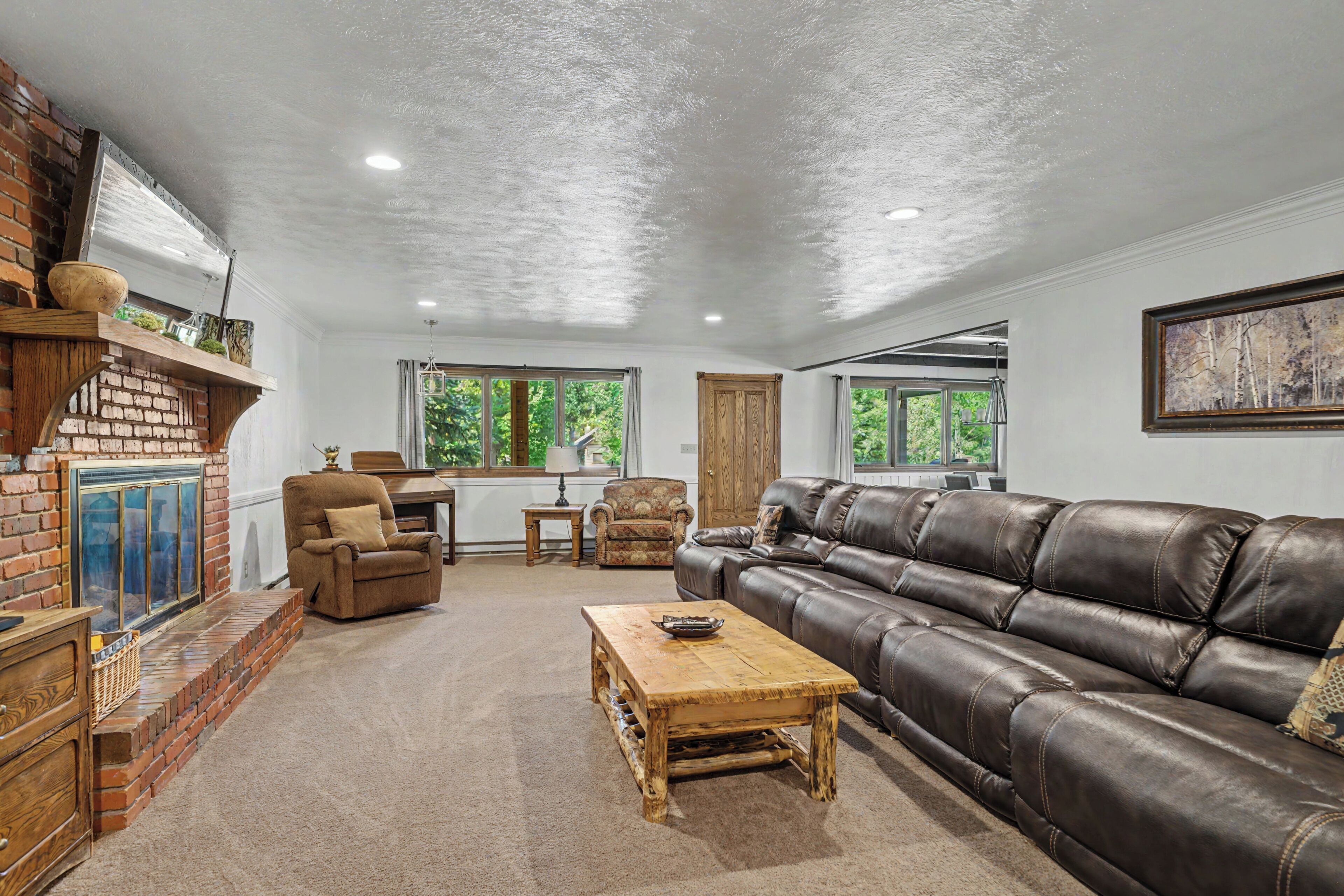 A living room with a brick fireplace, leather sofa, and a wooden coffee table.