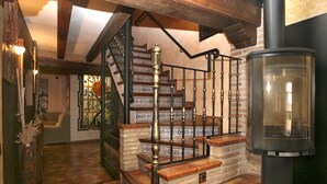 Un escalier orné de carreaux décoratifs et doté d’une rampe en métal noir, menant à une pièce avec une cheminée.
