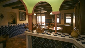 Une cuisine avec un dosseret de carrelage à motifs à carreaux, des armoires en bois et un coin repas comprenant des chaises et une table.