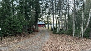 Ein bewaldetes Gebiet mit einem Kiesweg, der zu einer roten Holzhütte führt.