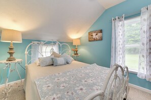 A bedroom with a bed, two bedside tables, a lamp, a window with curtains, and a wall-mounted artwork. - Visit Fife Lake & Traverse Bay! Farmhouse Hideaway (Fife Lake)