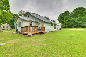 A single-story house with a wooden deck and a small porch. - Visit Fife Lake & Traverse Bay! Farmhouse Hideaway (Fife Lake)