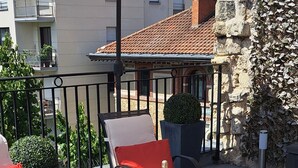 Une terrasse extérieure avec une table dressée pour deux personnes, agrémentée d’une bouteille de champagne et de verres.