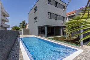 Een buitenzwembad, ligstoelen bij het zwembad