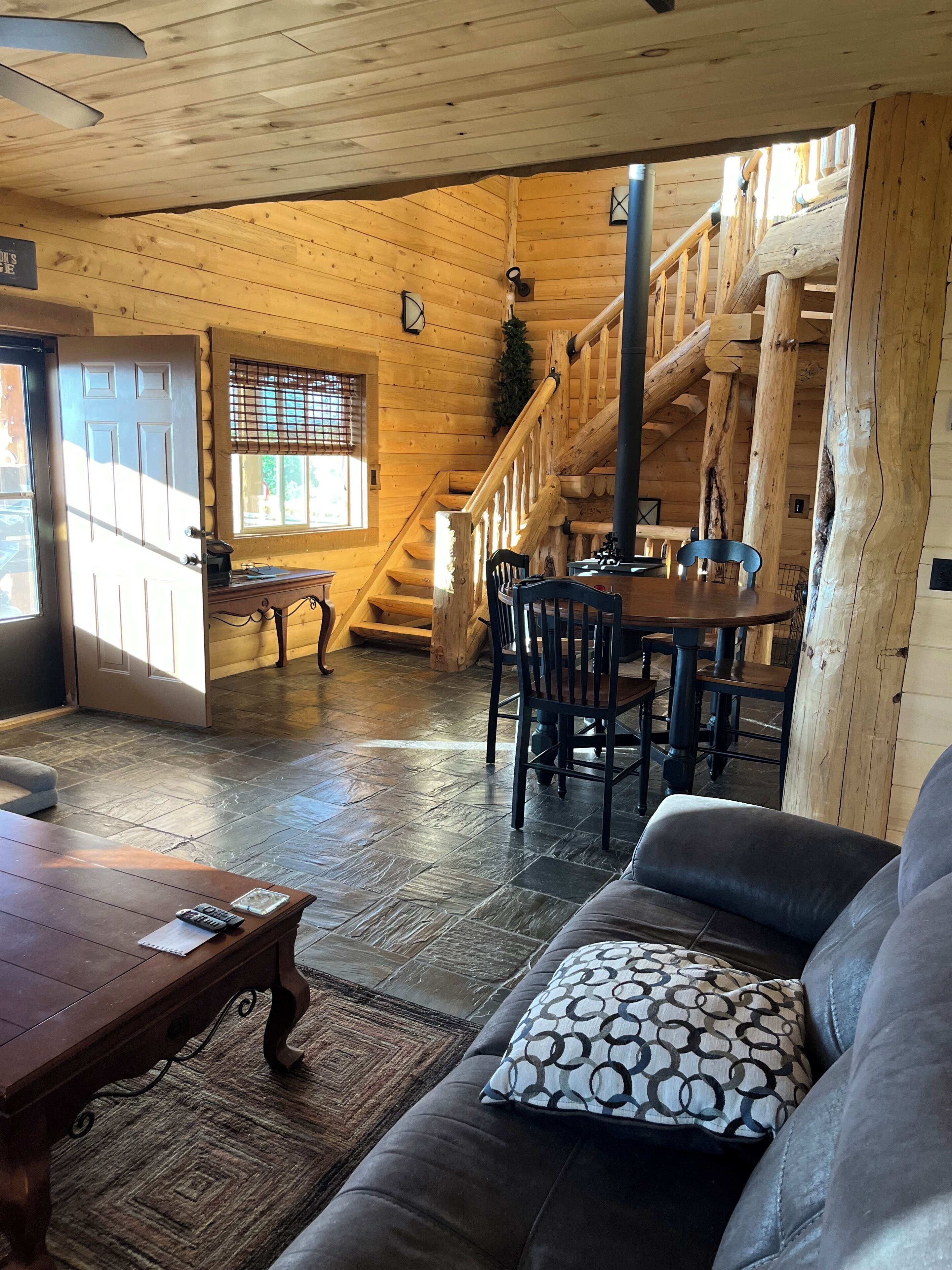 Interior de madera con una escalera, un comedor y una sala de estar con un sofá y una mesa.