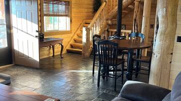 A wooden interior with a staircase, a dining area, and a seating area with a sofa and a table.