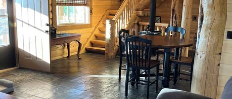 Interior de madera con una escalera, un comedor y una sala de estar con un sofá y una mesa.