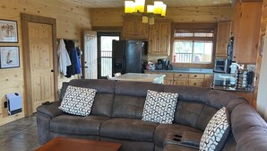 Un interior de madera con un sofá modular, una mesa de comedor de madera y una zona de cocina.