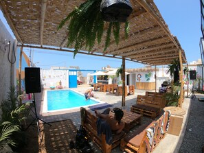 An outdoor pool area with wooden furniture and a covered seating area.