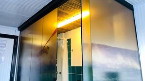 A room with a sliding door, a shower area, and a ceiling with a light fixture. - Surfari Punta Rocas (Punta Negra)
