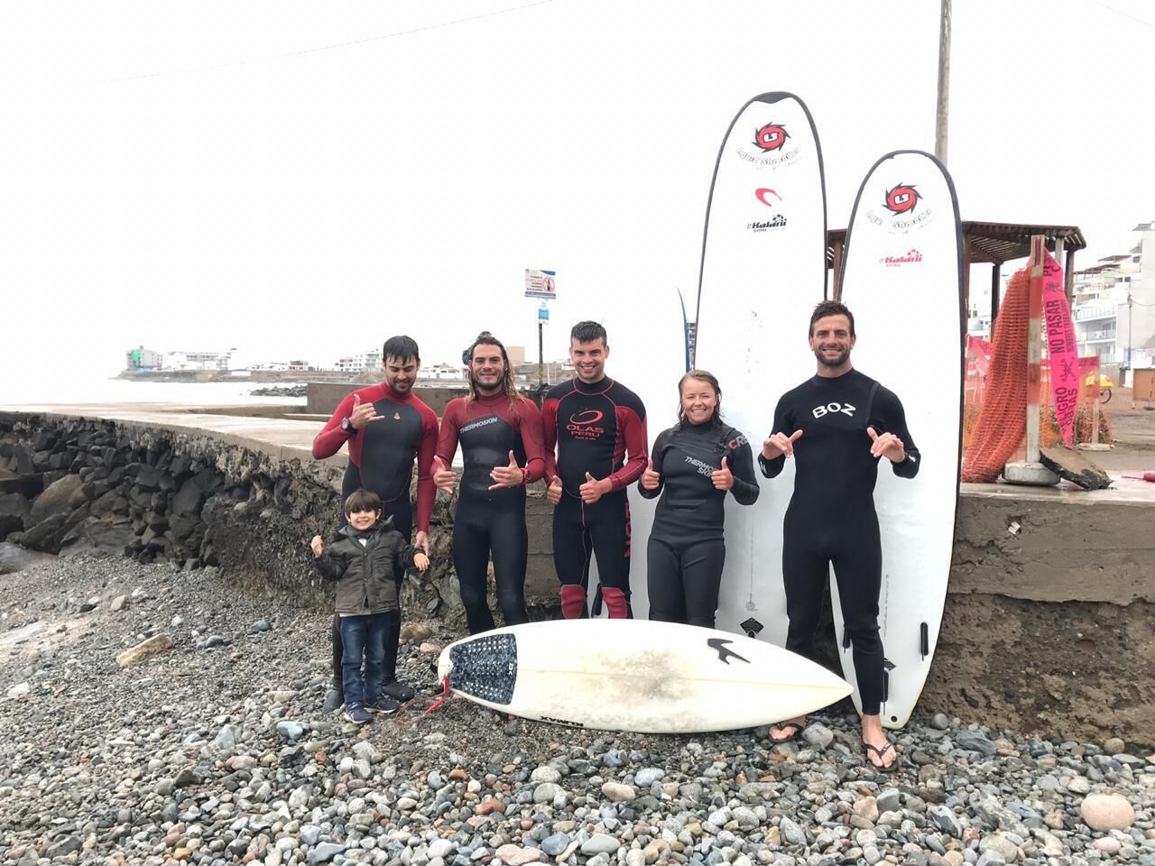 A group of people standing on a rocky beach with surfboards.