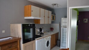 Una cocina compacta equipada con estufa, horno, microondas y lavadora.