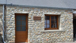 Edificio de piedra con puerta y ventana de madera, con el letrero 