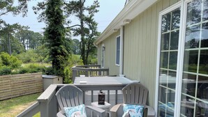 Une terrasse avec deux chaises et une table, entourée d’une clôture en bois et de verdure.