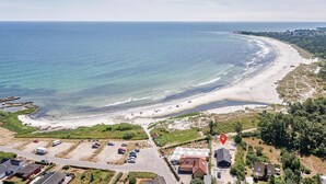 A coastal area with a beach, parking lot, and buildings.
