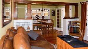 A living room with a brown leather sofa, wooden dining table, and chairs. There is a bookshelf with books and a framed picture on the wall. - Fabulous Downtown Living, 1 BR/1 BA  (Santa Barbara)