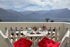 Een terras met een tafel gedekt voor twee, met uitzicht op een meer en bergen op de achtergrond.