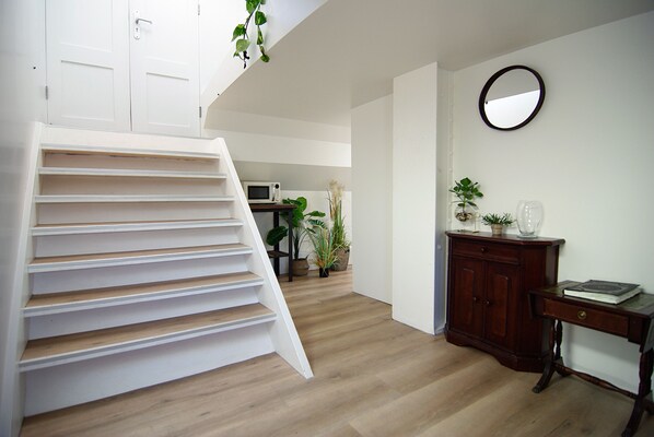 A staircase leading to a landing with a microwave and potted plants.