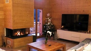 En hyggelig stue med pejs, tv og juletræ.