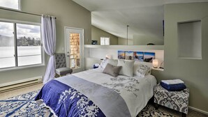 A bedroom with a large bed, a chair, a bedside table, and a window with curtains. - Waterfront DeRuyter Home w/ Private Dock! (DeRuyter)