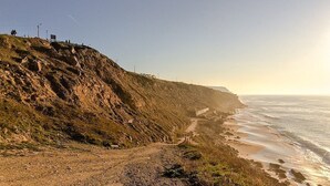Un sendero costero con un acantilado rocoso y vista al océano.