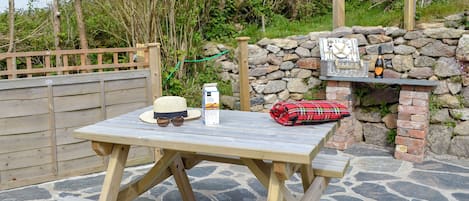 Una mesa de picnic de madera con una botella de leche, un sombrero y gafas de sol encima.