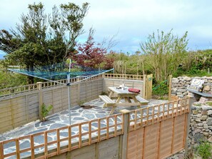 Une terrasse en bois avec un sol en pierre, une table de pique-nique et un fil à linge.