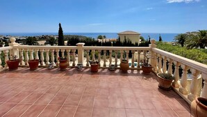 Eine Terrasse mit Terrakottafliesen, einem weißen Geländer und Kübelpflanzen.