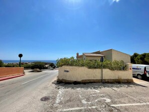 A coastal property with a small building, a clear road, and a van parked nearby.