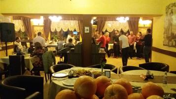 A restaurant with multiple tables, chairs, and a variety of dishes on the tables.