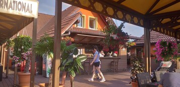 Un área de patio al aire libre con bar, asientos y plantas en macetas.