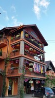 Un hotel con varios balcones decorados con plantas colgantes coloridas y banderas.