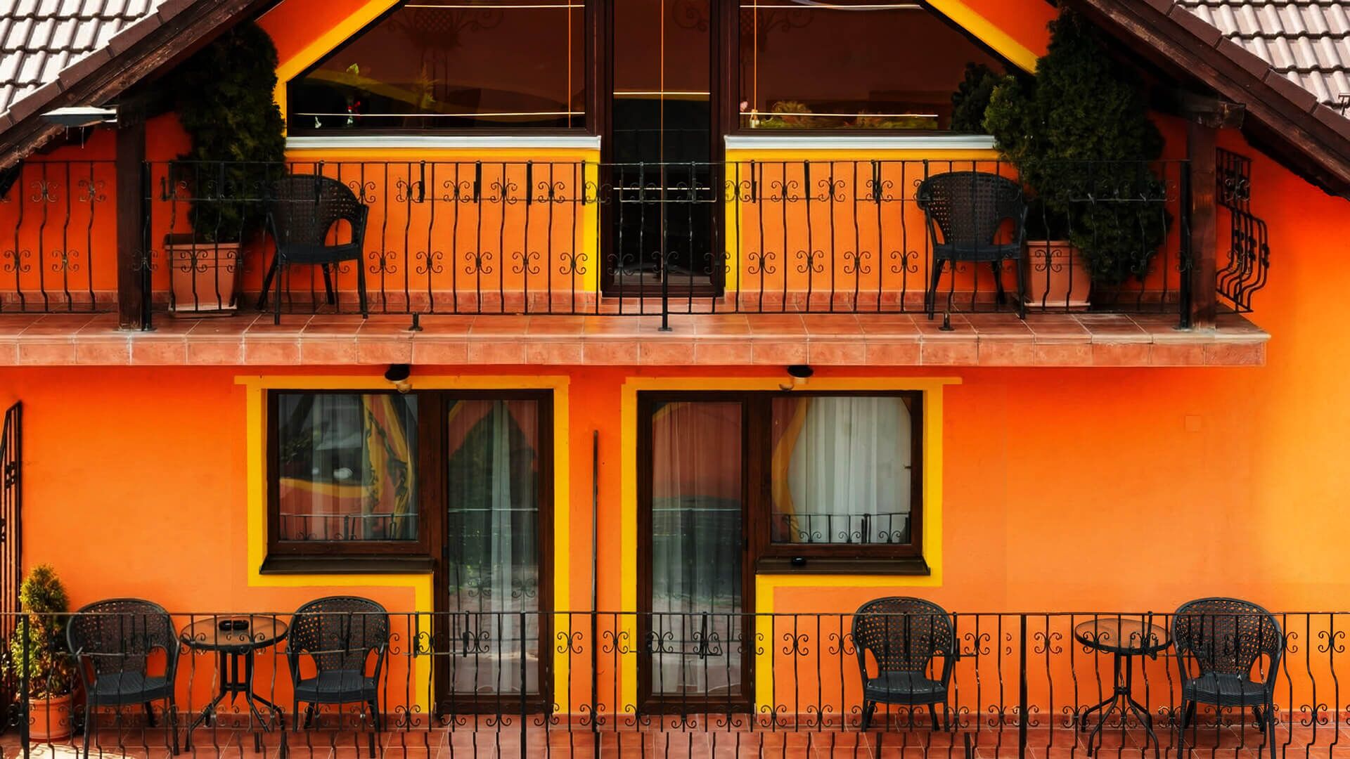 Un edificio de dos plantas con balcones, ventanas amplias y terraza.