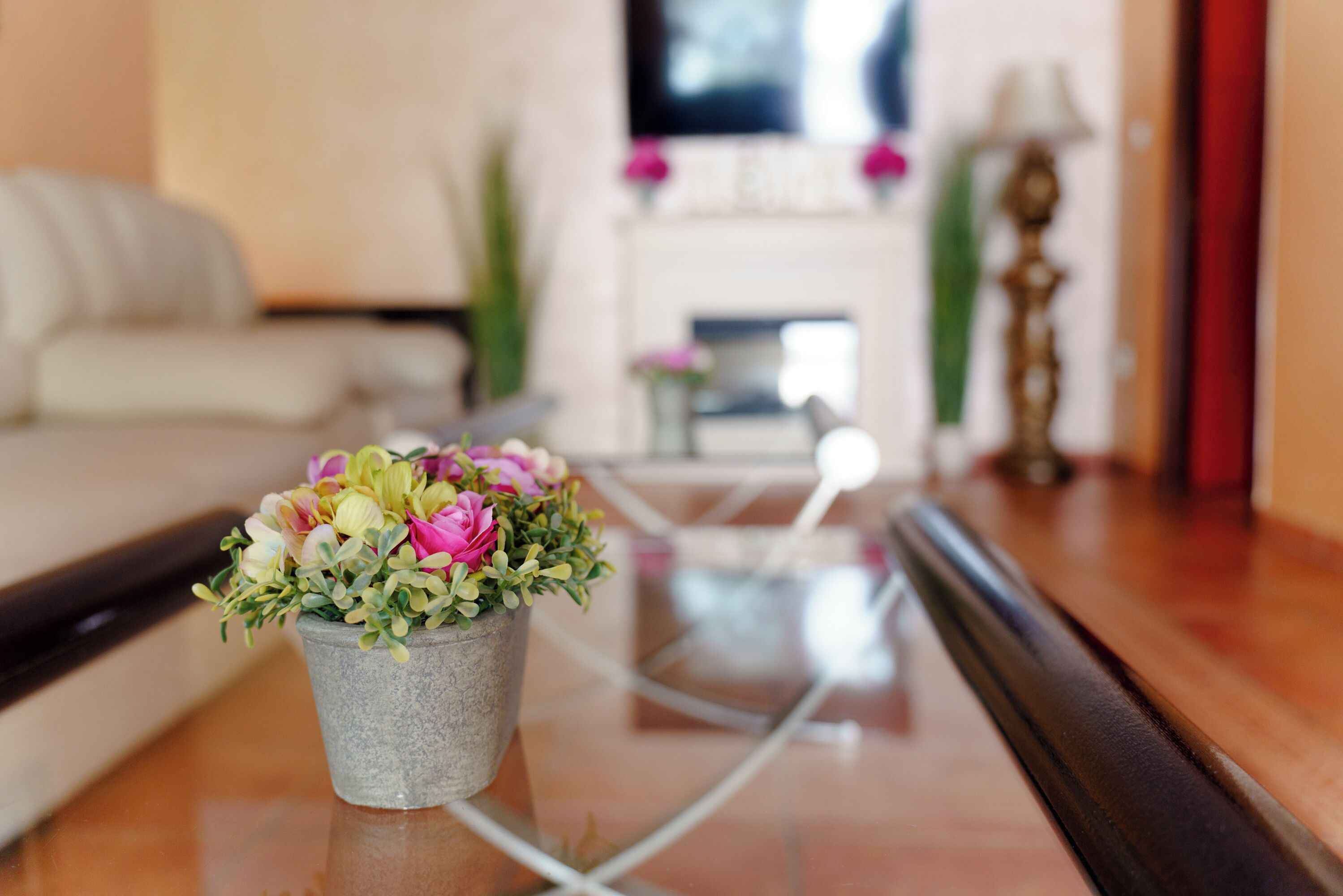 Una sala de estar con un sofá, una mesa de centro con un florero y una chimenea al fondo.
