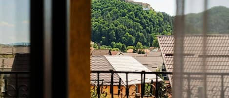 A view of a hilltop castle with the name 'RASNOV' visible, surrounded by buildings with tiled roofs.