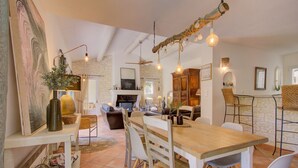 A dining area with a wooden table, chairs, and hanging light fixtures.